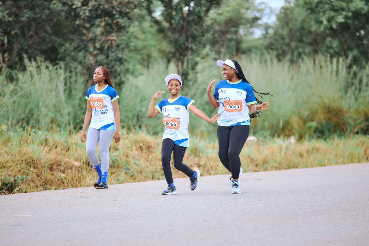 Three young runners enjoying their race on a tree-lined road